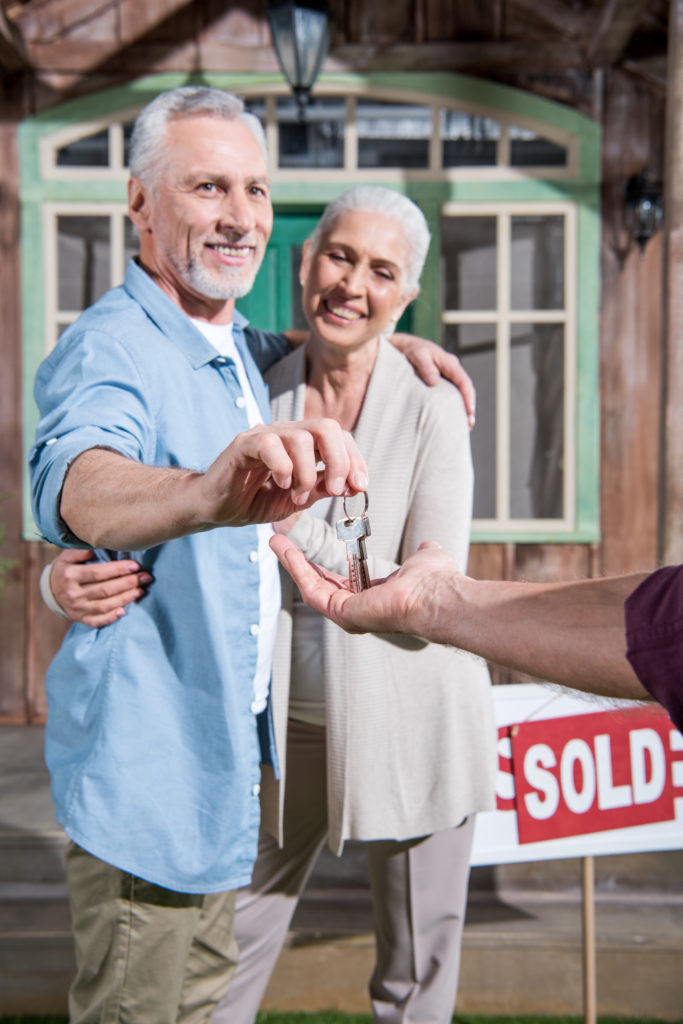 saleman giving keys of new house to happy senior couple